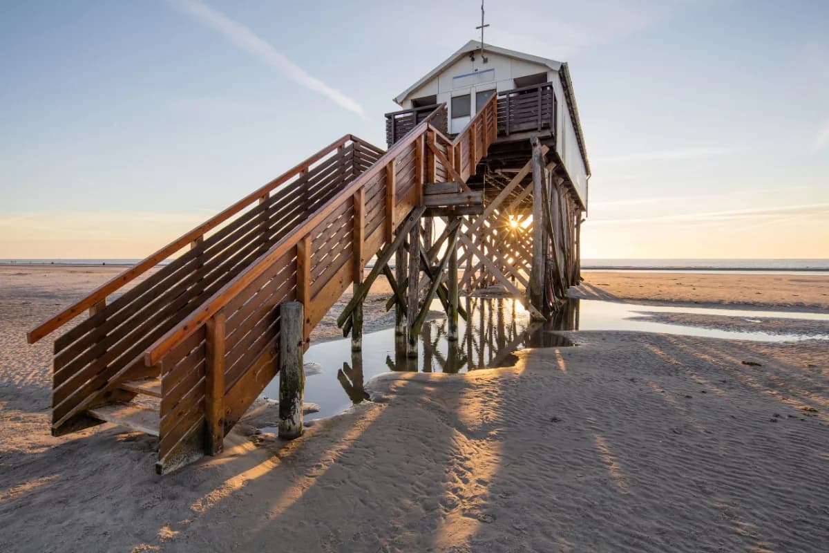 Pfahlbau mit Treppenaufgang am Strand von St. Peter-Ording bei Ebbe und Abendlicht
