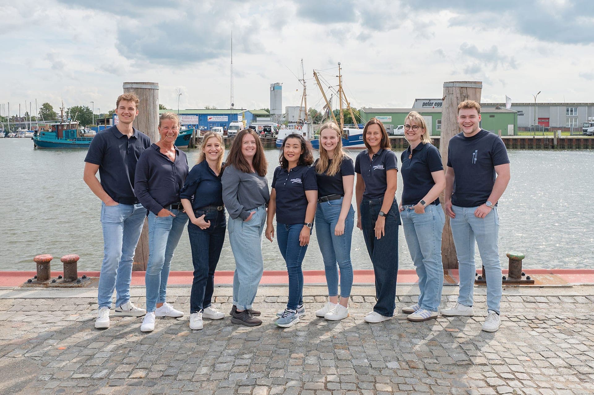 Team von Ferien an der Nordsee am Husumer Hafen, neun Mitarbeitende der Ferienhausvermittlung an der Nordseeküste